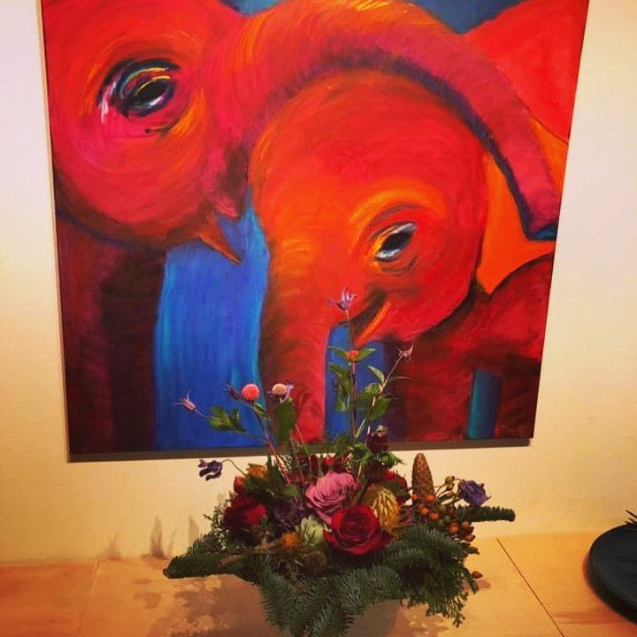 Flot farverigt maleri med to røde elefanter, der står kærligt sammen.